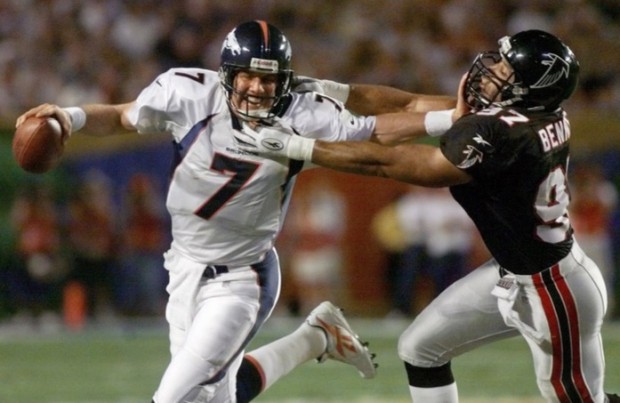 Quaterback do Denver Broncos e futuro Hall of Fame, John Elway, realizando um stiff-arm contra o linebacker do Falcons, Cornelius Bennett, durante o Super Bowl XXXIII em Miami. (AP Photo/Doug Mills).